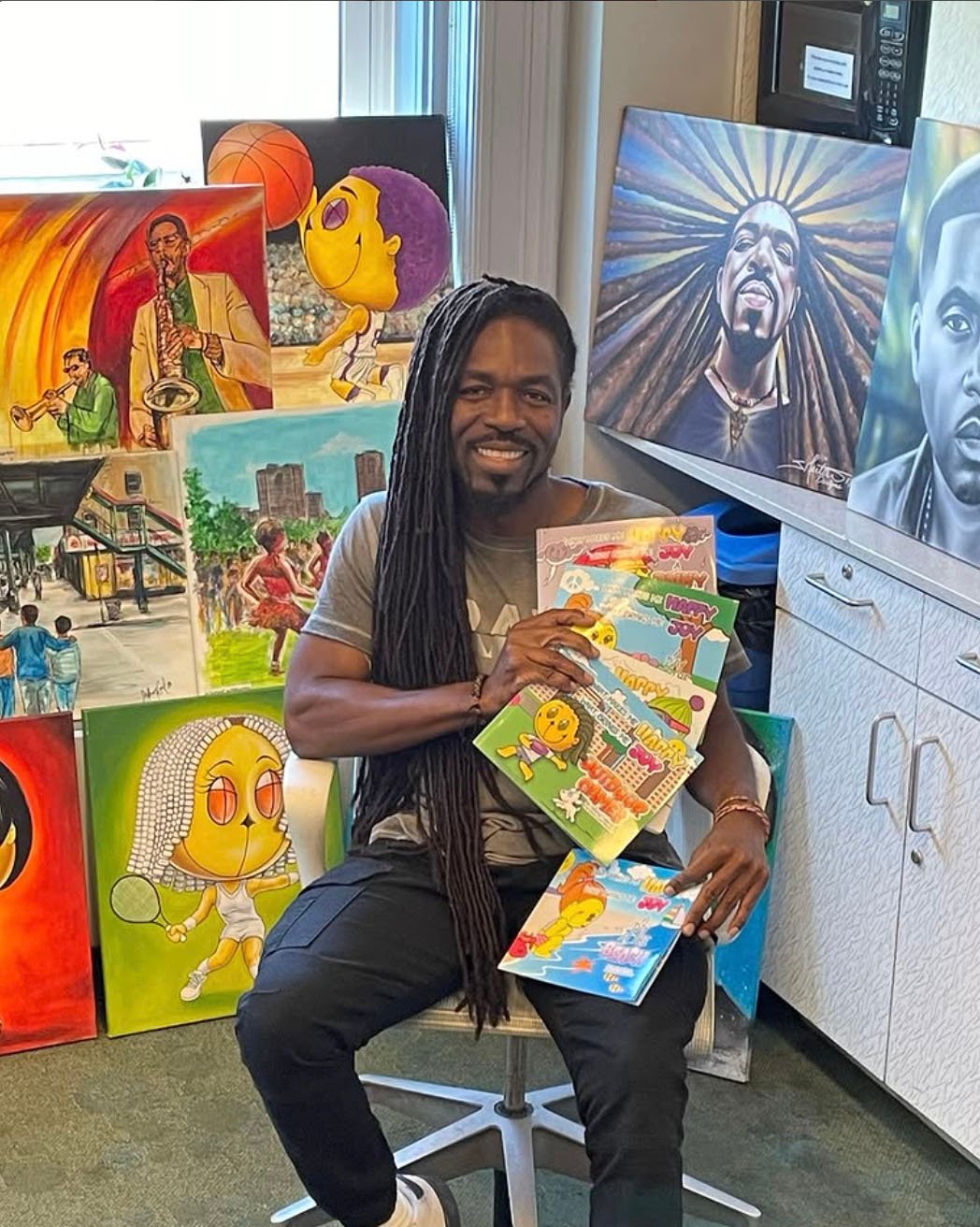 John Carl Martin with his paintings and Happy Island Books